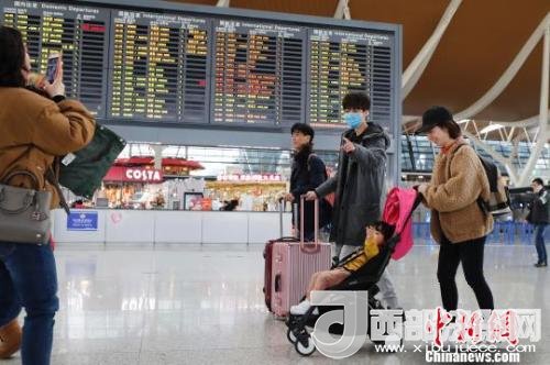 旅客帶著孩子前往辦票柜臺辦理登機手續(xù)?！∫罅⑶?攝