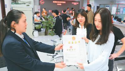 河北省承德市網(wǎng)絡(luò)代購(gòu)經(jīng)營(yíng)者陳晨(右)從工作人員手中接過(guò)帶有統(tǒng)一社會(huì)信用代碼的營(yíng)業(yè)執(zhí)照。 劉環(huán)宇攝(人民圖片)